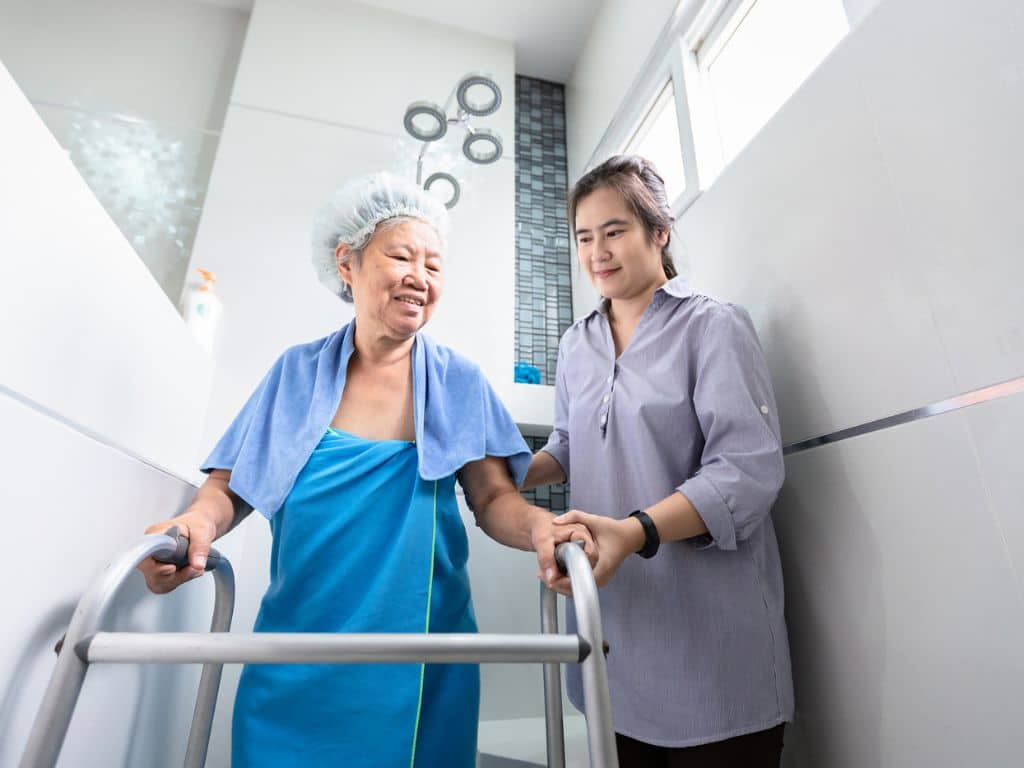 Lady helping senior take a shower